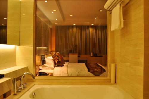a bathroom with a tub and a bed in a room at Suzhou Sun Plaza Hotel in Suzhou