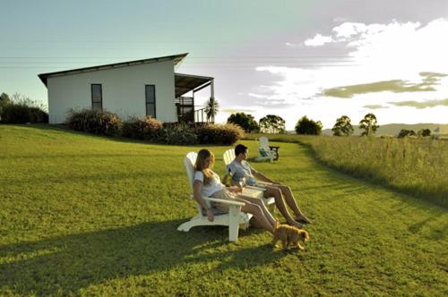 two people sitting on a chair in a field with a dog at Tonic Hotel in Lovedale
