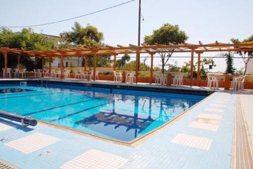 a large swimming pool with chairs and a pavilion at Hotel Aphroditi in Agia Paraskevi