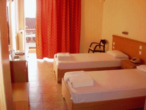 a hotel room with three beds and a window at Hotel Aphroditi in Agia Paraskevi