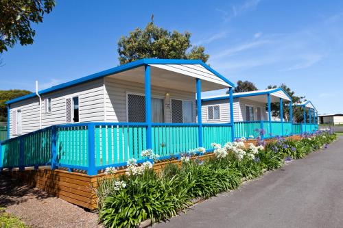 a blue and white house with flowers in front of it at Windang Tourist Park in Windang