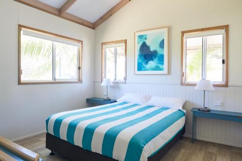 a bedroom with a bed and two windows at NRMA Port Macquarie Breakwall Holiday Park in Port Macquarie