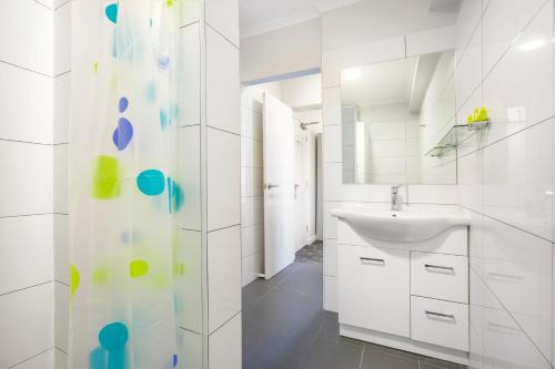 a white bathroom with a sink and a shower at Nightcap at Hume Hotel in Bankstown