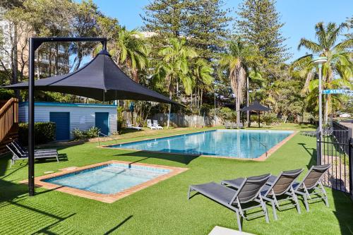 a swimming pool with chairs and an umbrella at NRMA Port Macquarie Breakwall Holiday Park in Port Macquarie