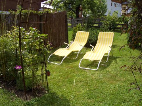 three chairs sitting in the grass in a yard at Gästehaus Burgi in Fügen