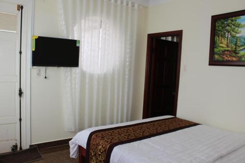 a bedroom with a bed and a flat screen tv at Thien Phu Guesthouse Dalat in Da Lat