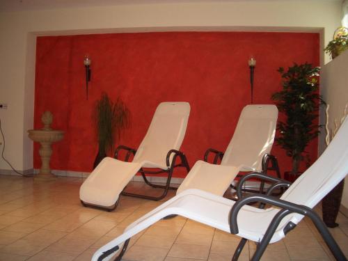 a room with white chairs and a red wall at Gästehaus Burgi in Fügen