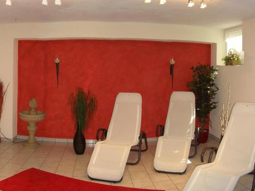 a room with four white chairs and a red wall at Gästehaus Burgi in Fügen