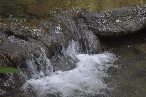 a stream of water rushing over a rock in a river at Thaweesuk Heritage Homestay in Phangnga