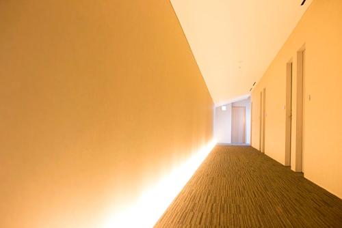 an empty hallway with a light on the wall at The Meibia Miyazaki in Miyazaki