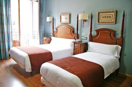 a bedroom with two beds and a window at Hostal Victoria II in Madrid
