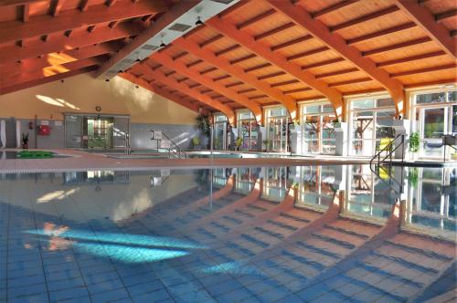 a swimming pool in a building with a wooden ceiling at Hotel Hajnal in Mezőkövesd