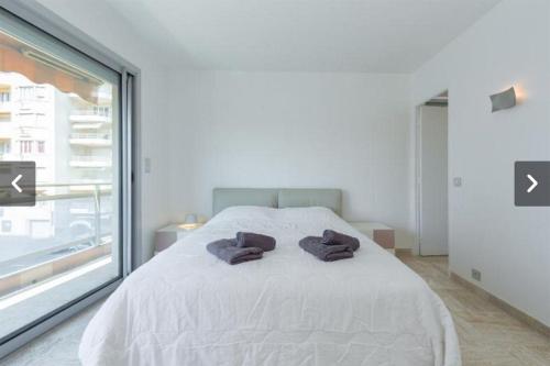 a bedroom with a white bed with two towels on it at Modern Croisette & Palm Beach in Cannes