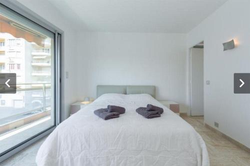 une chambre avec un lit blanc avec deux serviettes dessus dans l'établissement Modern Croisette & Palm Beach, à Cannes