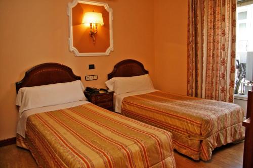 a hotel room with two beds and a mirror at Hostal Victoria II in Madrid
