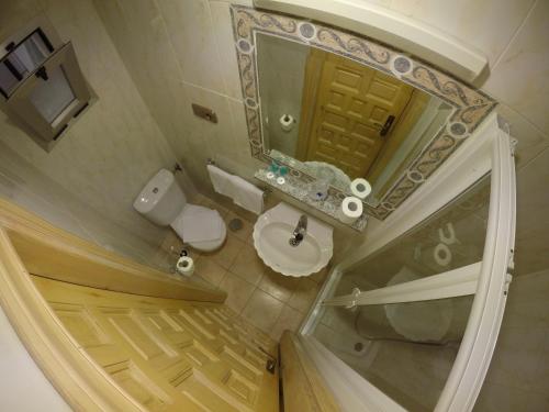 La petite salle de bains est pourvue d'un lavabo et d'un miroir. dans l'établissement Hostal La Casa de Enfrente, à Malaga