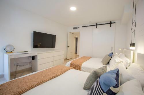 a hotel room with two beds and a tv at OCEAN VIEW DELUXE SUITE: PVT. BEACH & POOL in San Juan