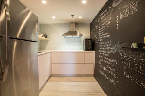 a kitchen with a refrigerator and a chalkboard wall at OCEAN VIEW DELUXE SUITE: PVT. BEACH & POOL in San Juan