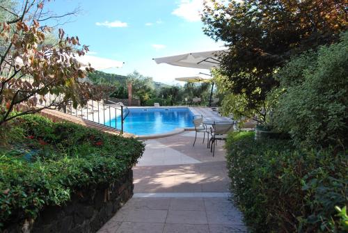 a swimming pool with a table and chairs and an umbrella at Tenuta Fortelongo in Fara Vicentino