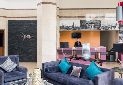 a lobby with two blue couches and a person in the background at Mercure St Helens in Saint Helens