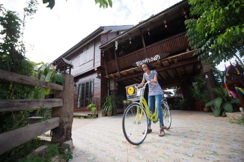 a woman riding a bike in front of a building at Khuang Chang Kam in Nan