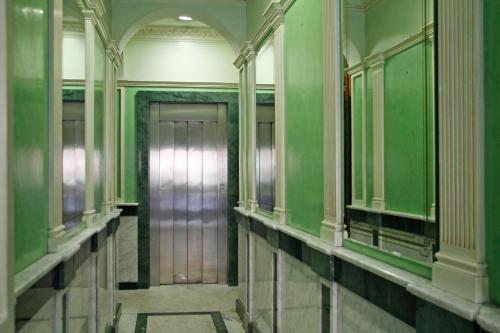 a hallway with green walls and a metal elevator at Hostal Victoria II in Madrid