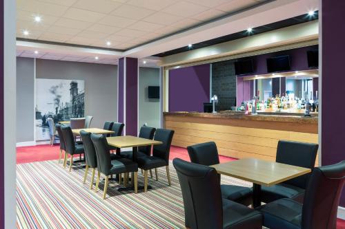 a restaurant with tables and chairs and a bar at Mercure St Helens in Saint Helens