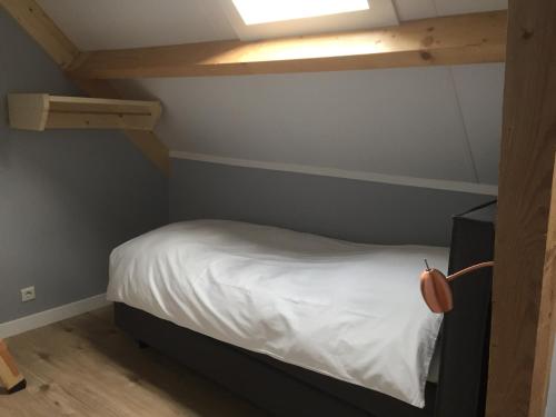a small bedroom with a bed with white sheets at B&B Erve ten Dam in Ambt Delden