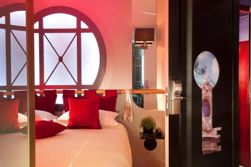une chambre avec un lit avec des oreillers rouges et une fenêtre dans l'établissement Secret de Paris - Hotel & Spa, à Paris