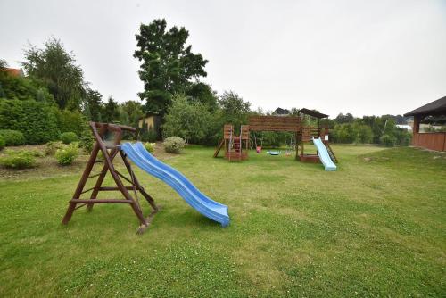 a playground with a slide and a swing set in a yard at Hotel Restauracja LORENZO in Stopnica