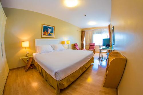 a bedroom with a bed and a desk with a television at Constellation Apartments in Kampala