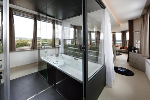 a bathroom with a glass shower and a tub at aquaTurm Hotel & Energie in Radolfzell am Bodensee