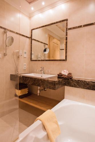 a bathroom with a tub and a sink and a mirror at Rimlhof by A CASA in Längenfeld