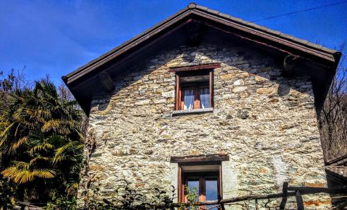 a stone house with two windows and a palm tree at Tenuta Casa Cima - tenutacasacima com - in Gudo
