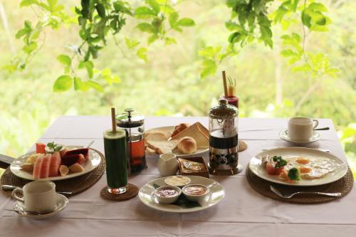 een tafel met borden eten op een tafel bij Bersila La Maison Du Bonheur in Payangan