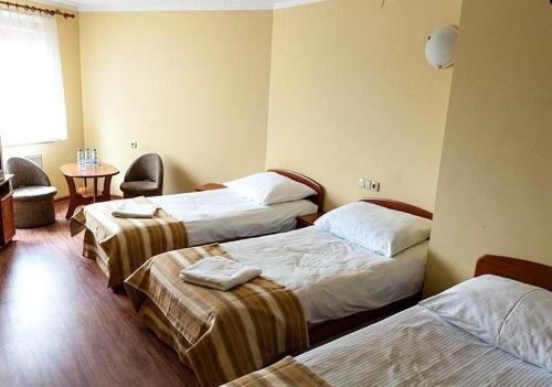 a hotel room with two beds and a table at Hotel Omega in Ostrów Wielkopolski