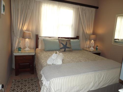 a bedroom with a bed with two lamps and a window at Stroke-One-Inn in Umkomaas