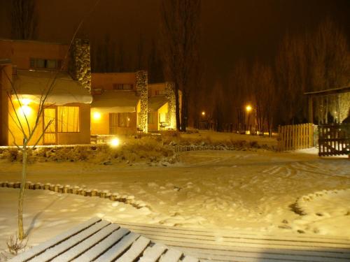 a snow covered yard with a house at night at Cabañas Monte Coiron in Malargüe