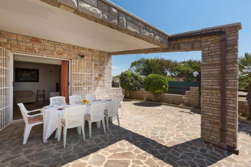 a patio with a table and chairs and a brick wall at Riva del Conte by BarbarHouse in Punta Prosciutto
