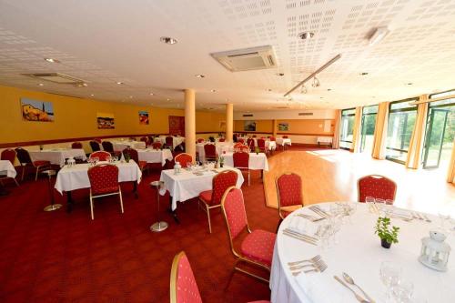a dining room with white tables and red chairs at Logis Hôtel - Restaurant Le Tulipier in Vienne-le-Château
