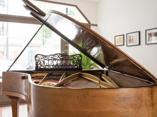 a wooden piano with a bench in a room at Hôtel des Batignolles in Paris