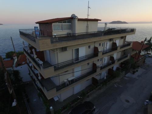 a building with a balcony on top of it next to the water at Akrotiri Hotel in Neos Marmaras