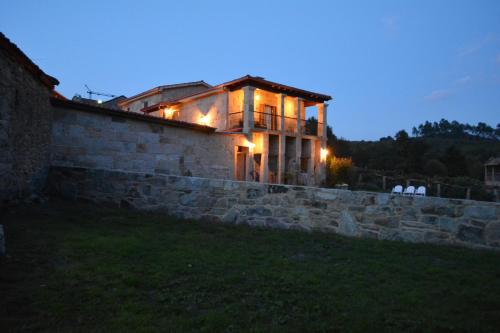 a house with lights on top of a stone wall at Alojamiento Pazos in Cea