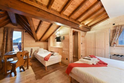 a bedroom with two beds and a desk in a room at Loc'Hotel Alpen Sports in Les Gets