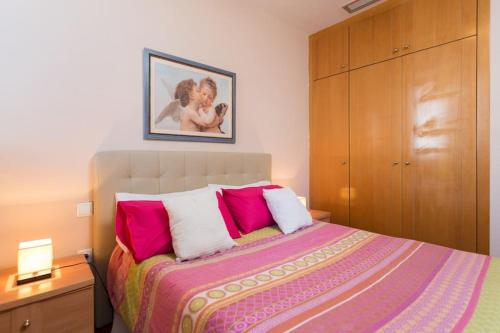 1 dormitorio con 1 cama con almohadas rosas y blancas en Apartamento Torre Uno Santa Cruz, en Santa Cruz de Tenerife