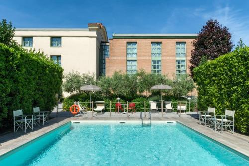 une piscine avec des chaises et des tables ainsi qu'un bâtiment dans l'établissement Hotel San Marco, à Lucques