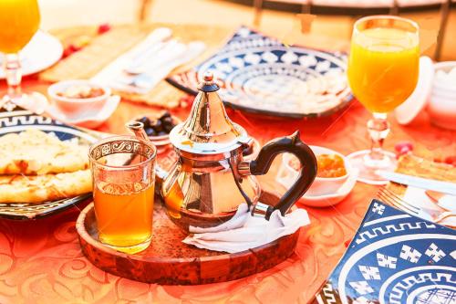 einen Tisch mit einem Wasserkocher und Gläsern Orangensaft in der Unterkunft Jad Auberge in Ourika