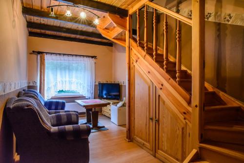 a living room with two chairs and a staircase at Chata Baryła in Sulęczyno