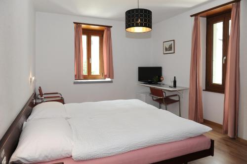 una camera con letto bianco, scrivania e finestre di La Dent-du-Midi Hôtel & Restaurant a Saint-Maurice