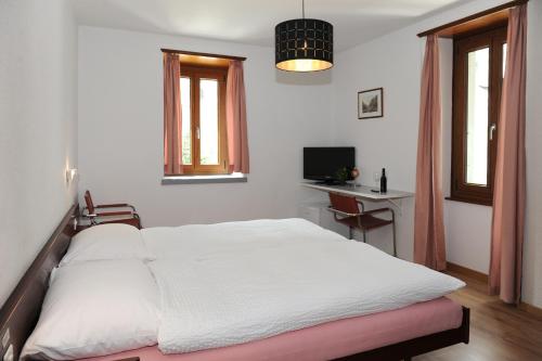Schlafzimmer mit einem weißen Bett, einem Schreibtisch und Fenstern in der Unterkunft La Dent-du-Midi Hôtel & Restaurant in Saint-Maurice